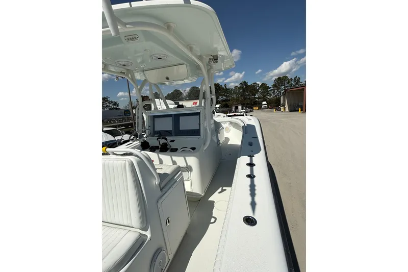 Slide: The Image of 2013 Yellowfin 32 Offshore boat interior with seating and console, parked outdoors. - 15