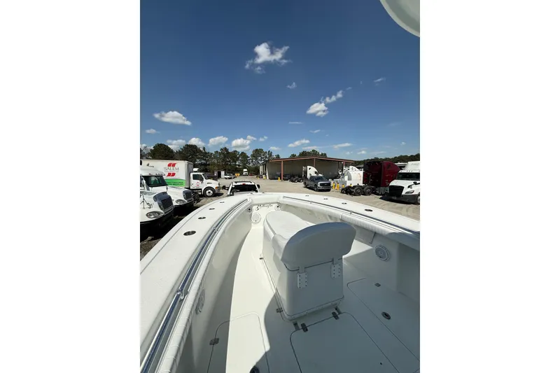 Slide: The Image of 2013 Yellowfin 32 Offshore boat interior with seating, parked near trucks under a clear sky. - 6