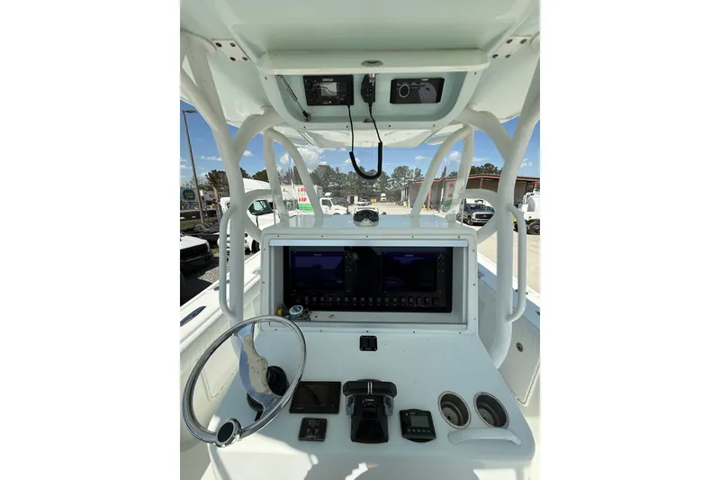 Slide: The Image of 2013 Yellowfin 32 Offshore boat interior with clear sky and parked trucks in background. - 7