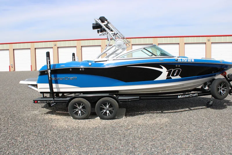 Slide: The Image of 2013 MasterCraft X10 boat on trailer in front of storage buildings. - 12