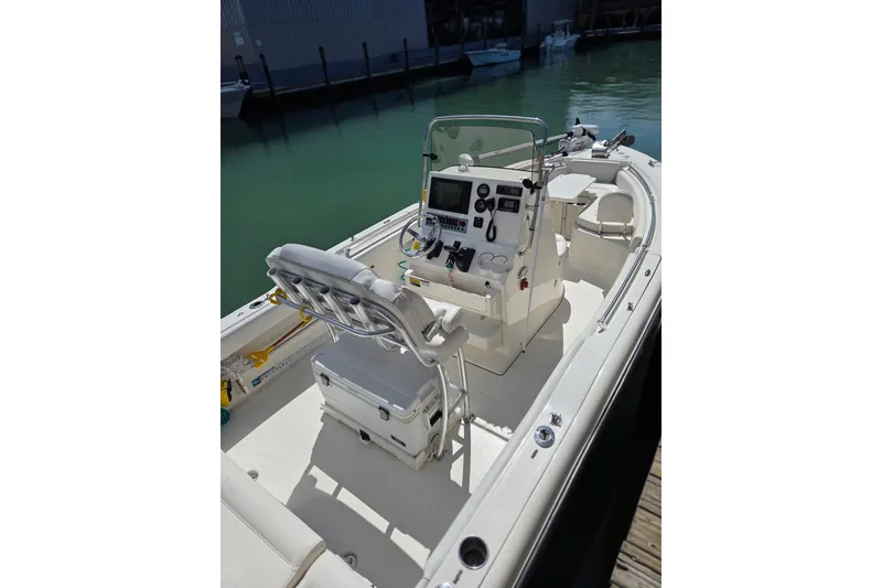 Slide: The Image of 2022 Key West 219 FS boat interior with helm, seating, and controls docked by water. - 12