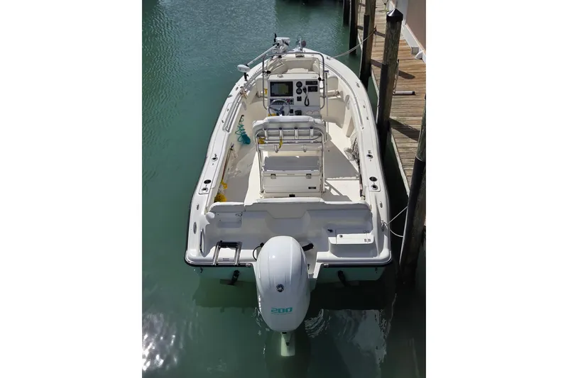 Slide: The Image of 2022 Key West 219 FS boat docked in calm water, showcasing its sleek design and outboard motor. - 4