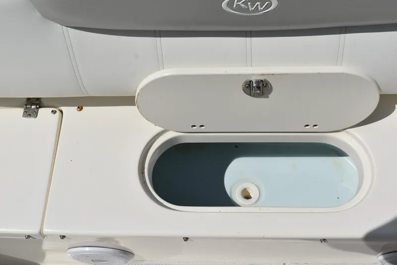 Slide: The Image of Key West 219 FS 2022 boat storage compartment with open lid and drain plug. - 7