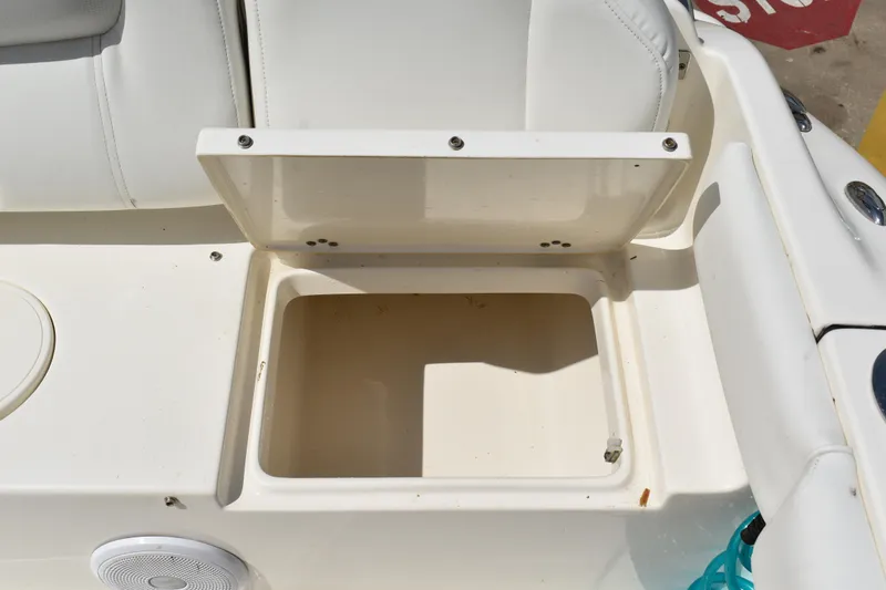 Slide: The Image of Open storage compartment on 2022 Key West 219 FS boat, featuring white seating and speaker. - 8