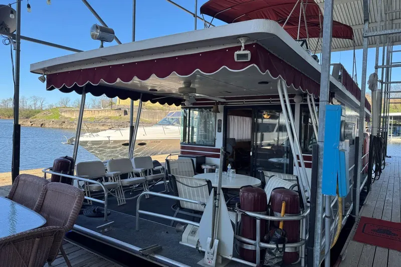Slide: The Image of 1987 Stardust Cruisers 14 x 54 houseboat docked, featuring outdoor seating and maroon canopy. - 3