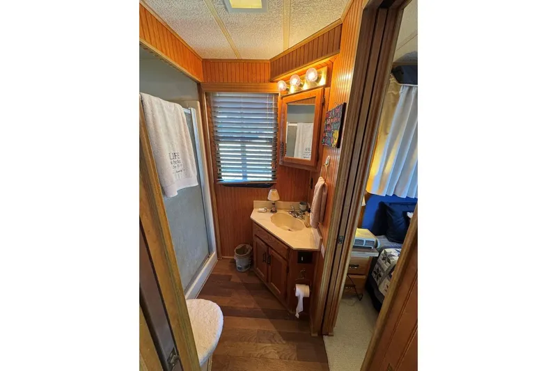 Slide: The Image of Bathroom interior of a 1987 Stardust Cruisers 14 x 54 houseboat, featuring wood paneling and vanity. - 36