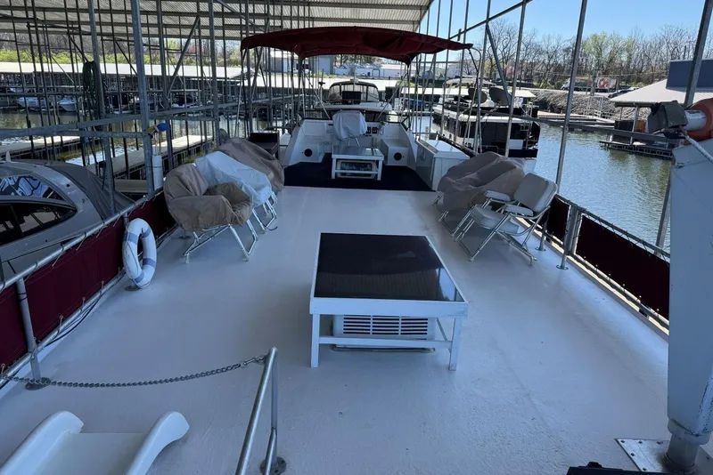 Slide: The Image of 1987 Stardust Cruisers 14 x 54 houseboat docked, featuring spacious deck with covered seating. - 47