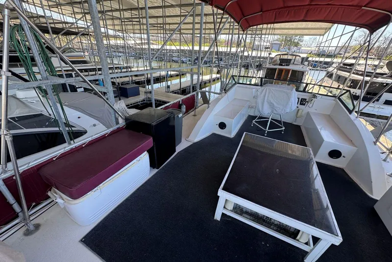 Slide: The Image of 1987 Stardust Cruisers 14 x 54 houseboat interior with seating and table under covered dock. - 51