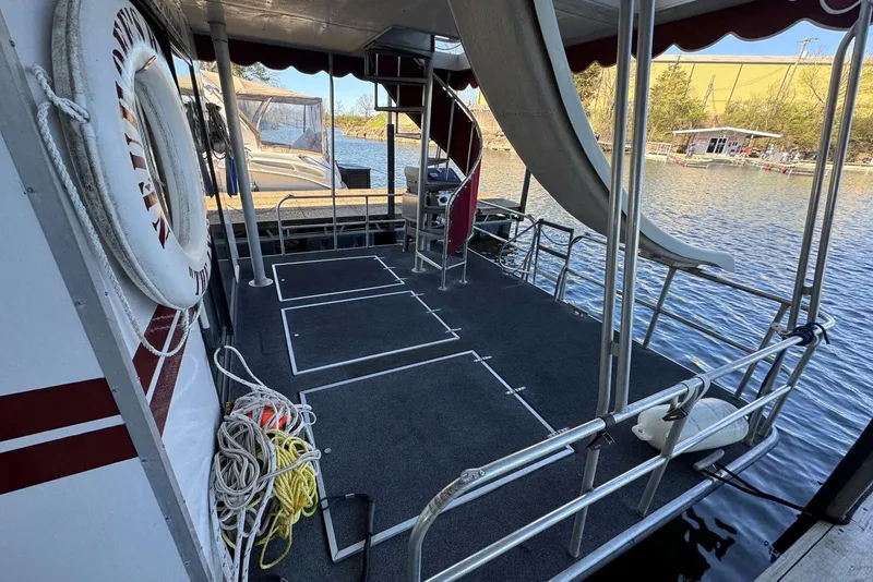 Slide: The Image of 1987 Stardust Cruisers houseboat deck with slide, ropes, and life preserver by the water. - 6