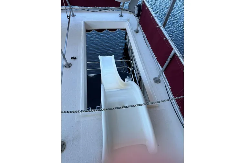 Slide: The Image of 1987 Stardust Cruisers houseboat with slide, red railing, and water view. - 60