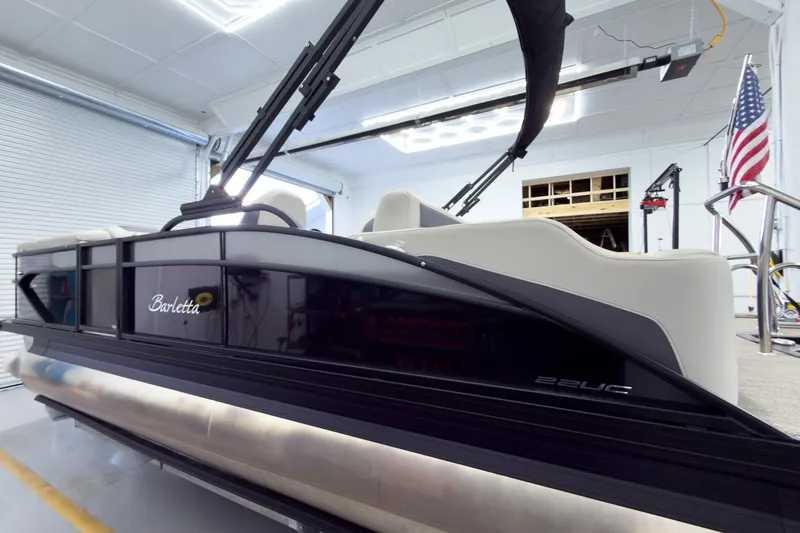 Slide: The Image of 2025 Barletta Cabrio 22UC pontoon boat in a garage with American flag. - 2