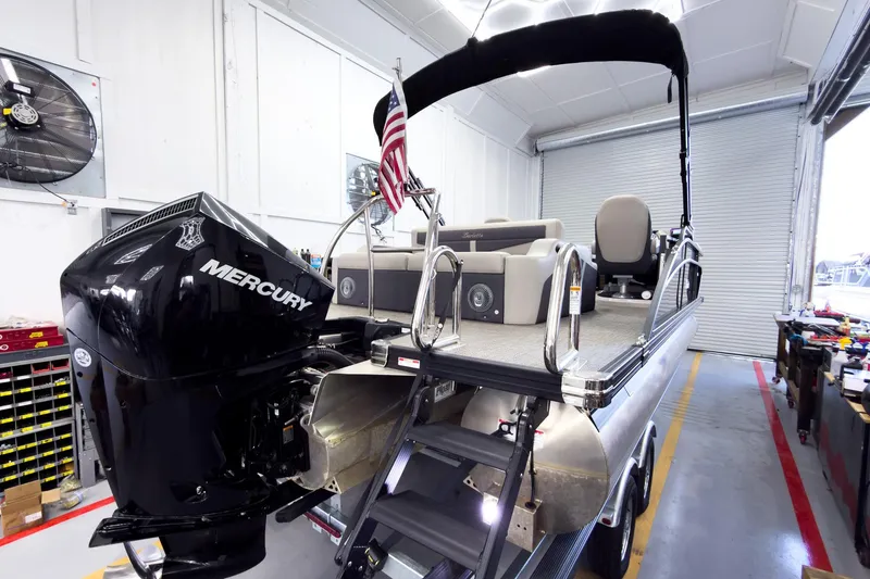Slide: The Image of 2025 Barletta Cabrio 22UC pontoon boat with Mercury engine in a workshop setting. - 5