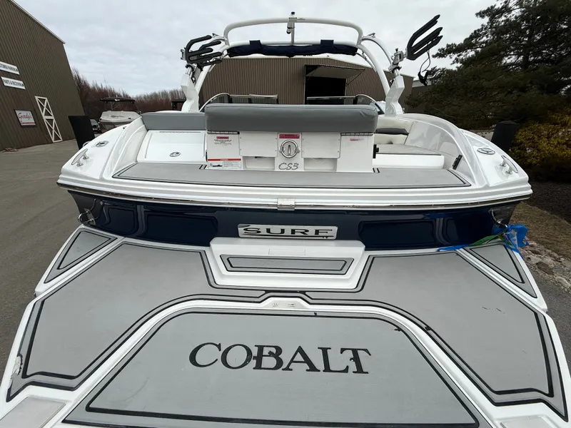 Slide: The Image of Rear view of a 2022 Cobalt CS23 Surf boat in a parking area. - 27