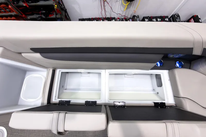 Slide: The Image of 2025 Barletta Cabrio 24UC boat interior storage compartments with beige seating and cup holders. - 14