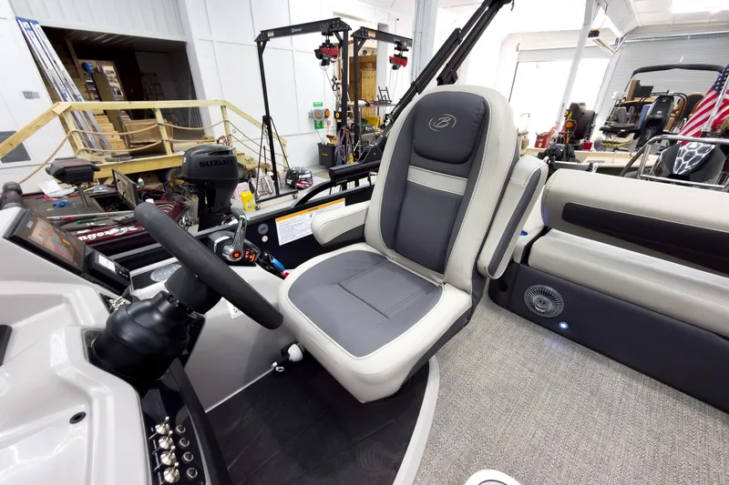 Slide: The Image of 2025 Barletta Cabrio 24UC boat interior with steering wheel and seating in a workshop setting. - 18