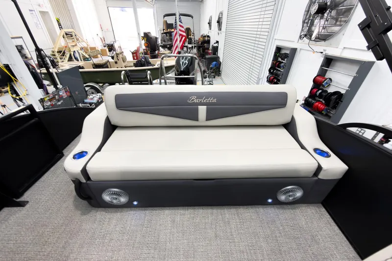Slide: The Image of 2025 Barletta Cabrio 24UC boat interior with plush seating and cup holders in a showroom. - 23