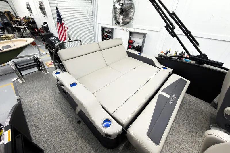 Slide: The Image of 2025 Barletta Cabrio 24UC boat interior with convertible seating and cup holders in a garage setting. - 28