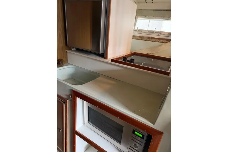 Slide: The Image of 1974 Magnum Sportfisher boat kitchen with sink, microwave, and stove. - 13
