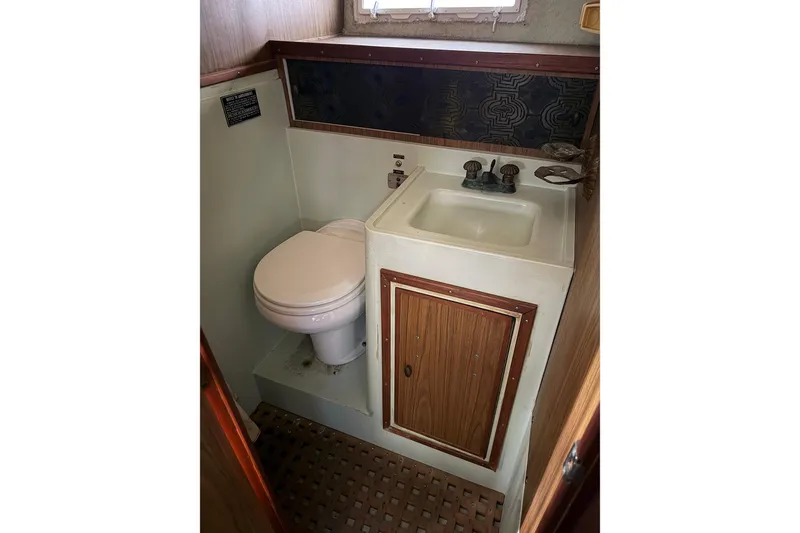 Slide: The Image of 1974 Magnum Sportfisher boat bathroom with toilet, sink, and wooden cabinetry. - 20