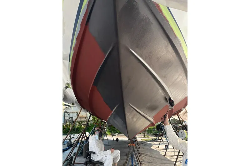 Slide: The Image of 1974 Magnum Sportfisher boat undergoing maintenance with workers in protective gear. - 6