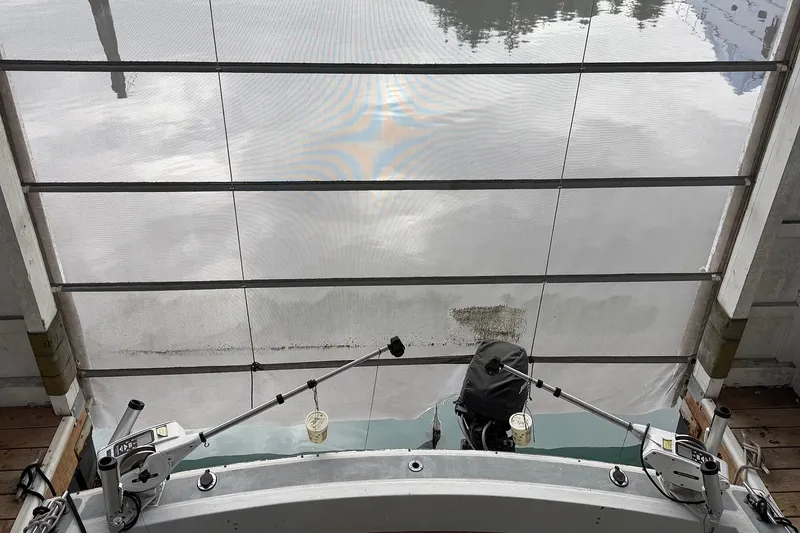 Slide: The Image of 1974 Magnum Sportfisher boat docked, featuring fishing rods and calm water reflection. - 8