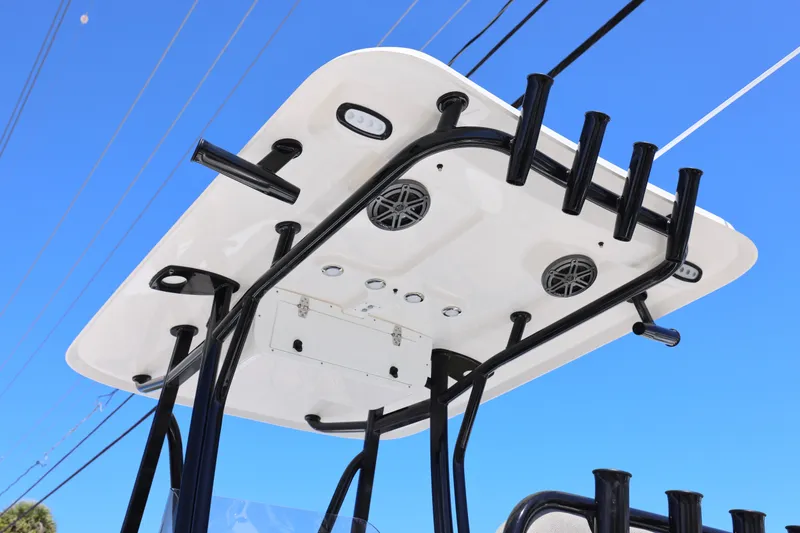 Slide: The Image of T-top of 2026 Sea Hunt Ultra 219 boat with rod holders and speakers against blue sky. - 18
