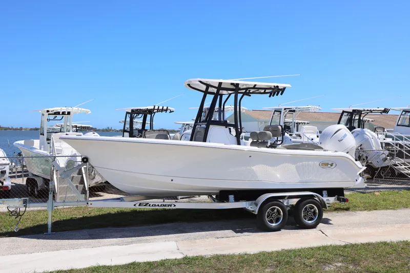 Slide: The Image of 2026 Sea Hunt Ultra 219 boat on trailer by waterfront, clear blue sky. - 19