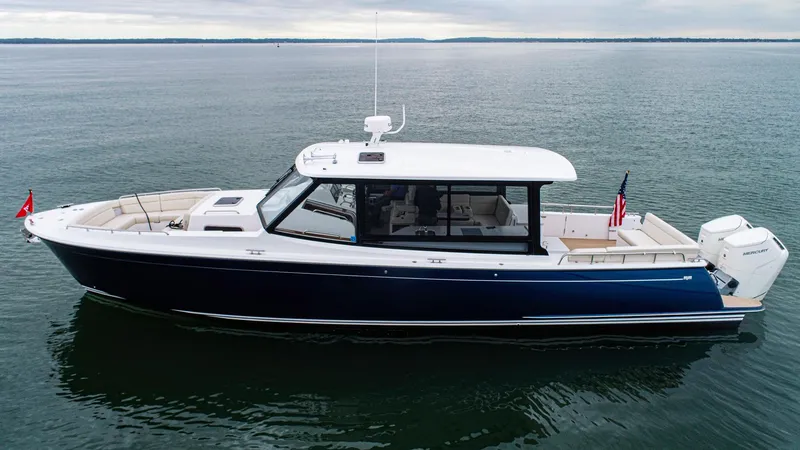 The Image of 2024 MJM 4 boat on calm water, sleek design, navy hull, white deck. - 0