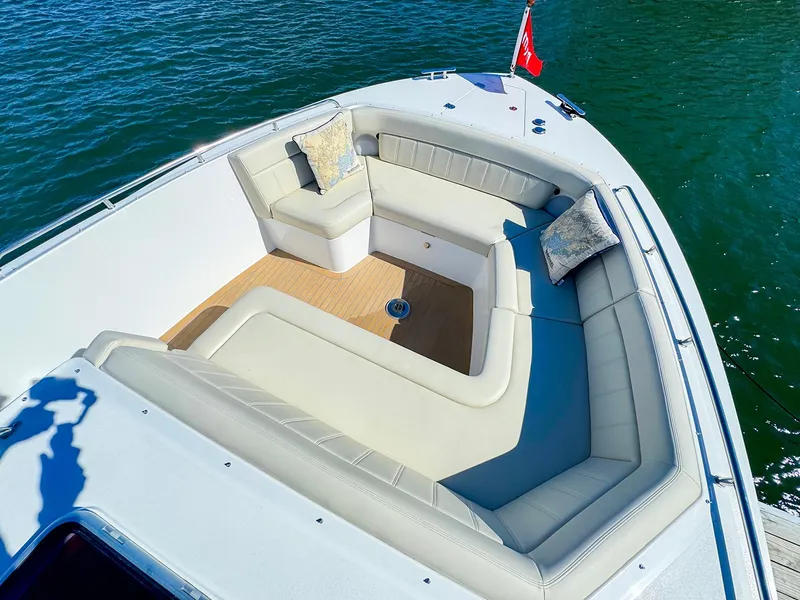 Slide: The Image of Luxurious seating area on 2024 MJM 4 boat, with cushions and flag, on water. - 11