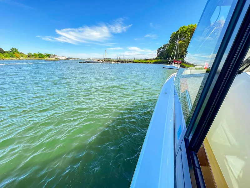 Slide: The Image of 2024 MJM 4 boat cruising on a sunny day near a lush shoreline. - 27