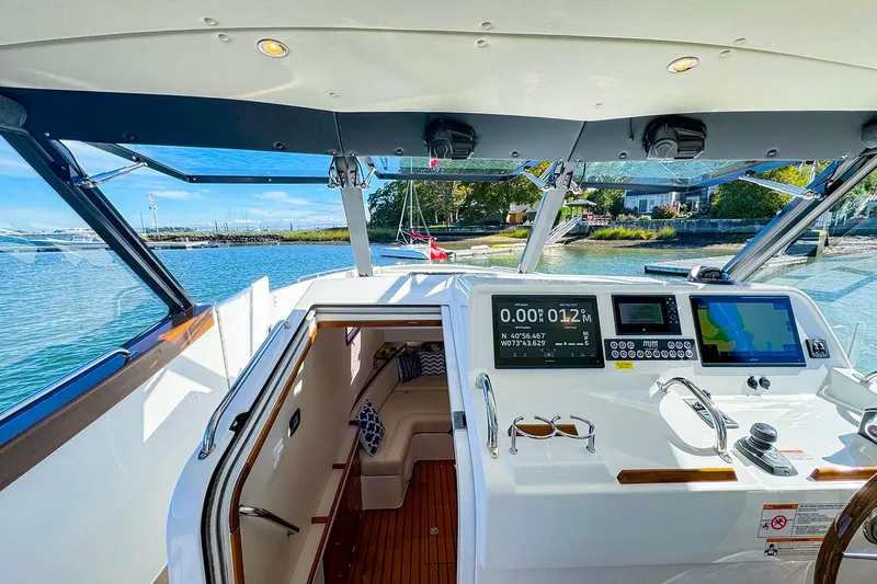 Slide: The Image of 2024 MJM 4 yacht cockpit with navigation screens, overlooking serene waters and lush shoreline. - 29