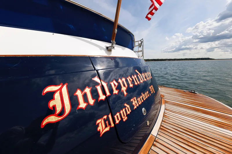 Slide: The Image of 2009 Hunt Yachts 52 Express named "Independence" on water, wooden deck, American flag. - 15