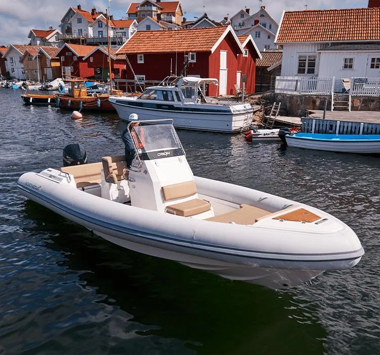 The Image of 2023 Northstar Orion 7 boat docked near red-roofed houses in a scenic harbor. - 0