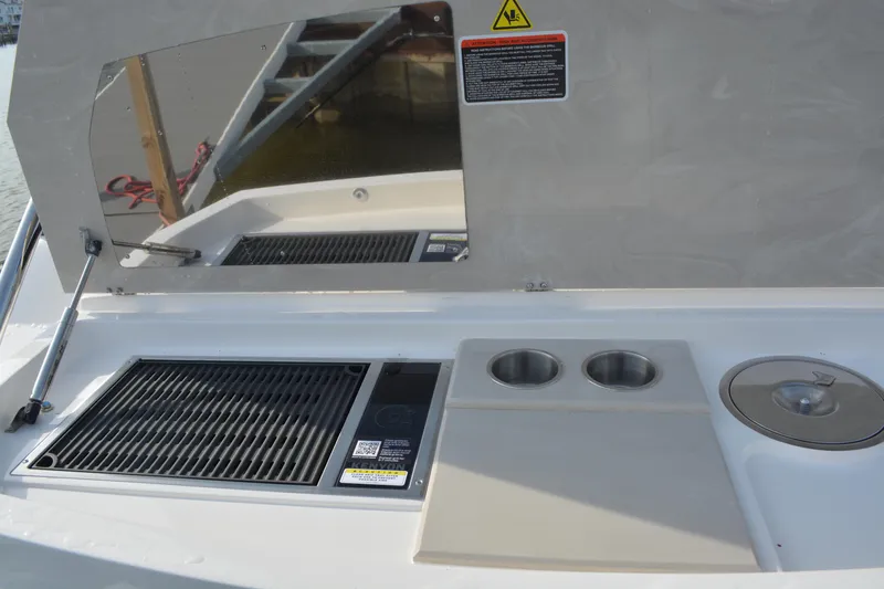 Slide: The Image of Outdoor kitchen area on 2026 NX Boats 360 Sport Coupe, featuring grill and cup holders. - 14