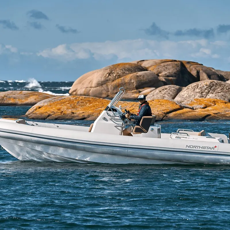 Slide: The Image of 2023 Northstar Orion 7 boat navigating near rocky coastline under clear sky. - 2