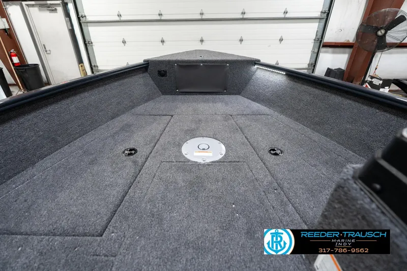 Slide: The Image of 2026 Lund 1775 Adventure SS boat interior with carpeted deck in a garage setting. - 15