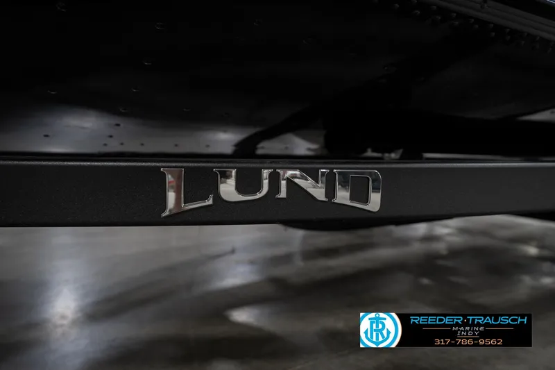 Slide: The Image of 2026 Lund 1775 Adventure SS boat logo on a black surface, showroom setting. - 48