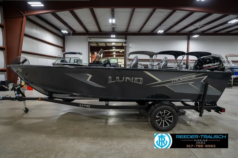 Slide: The Image of 2026 Lund 1775 Adventure SS boat in showroom, side view with trailer and Mercury engine. - 8
