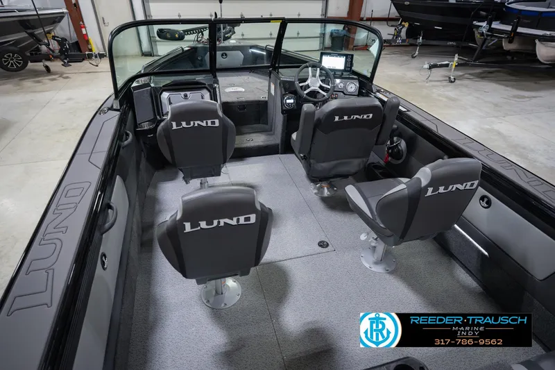 Slide: The Image of 2026 Lund 1975 Tyee boat interior with four seats and modern dashboard in a showroom. - 14