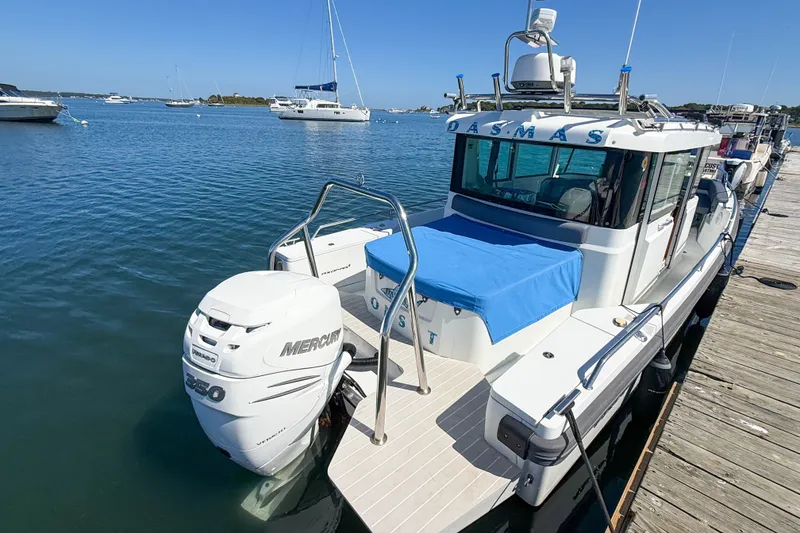 Slide: The Image of 2020 Axopar 28 Cabin boat docked with Mercury 350 engine, blue cover, and clear skies. - 27