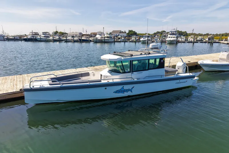 The Image of 2020 Axopar 28 Cabin boat docked at a marina, calm water, clear sky. - 0