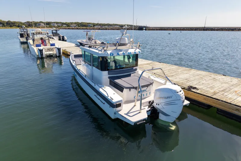 Slide: The Image of 2020 Axopar 28 Cabin boat docked at a marina with clear blue water. - 30