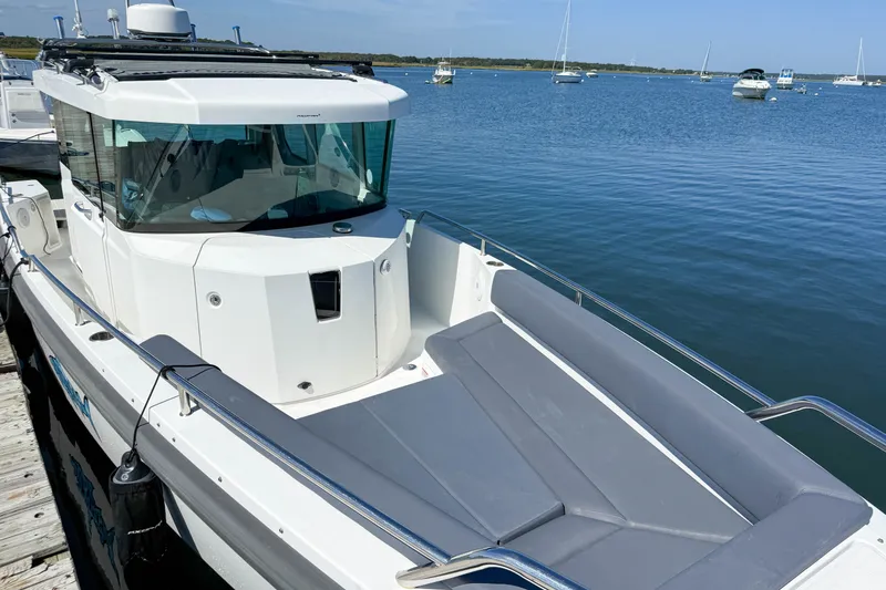 Slide: The Image of 2020 Axopar 28 Cabin boat docked on calm water with clear blue sky. - 10