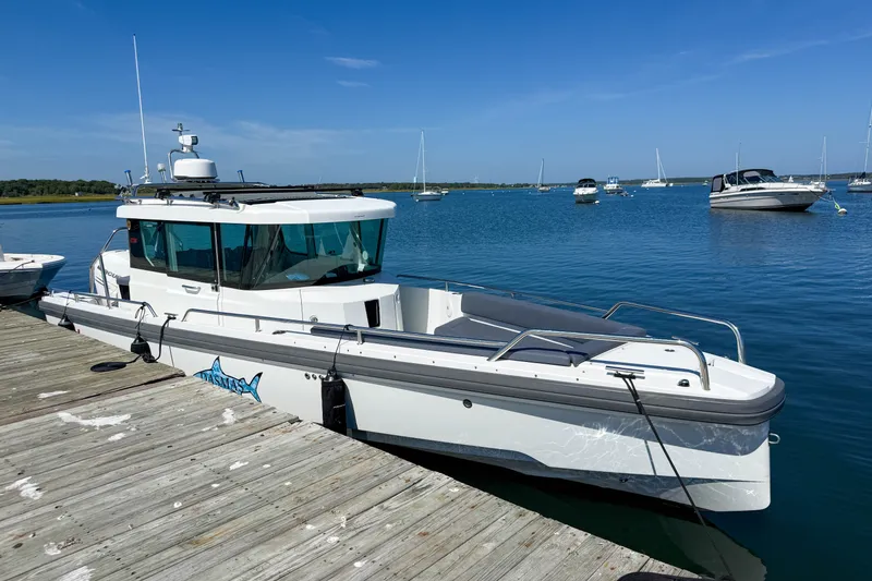 Slide: The Image of 2020 Axopar 28 Cabin boat docked on a sunny day with clear blue water. - 2