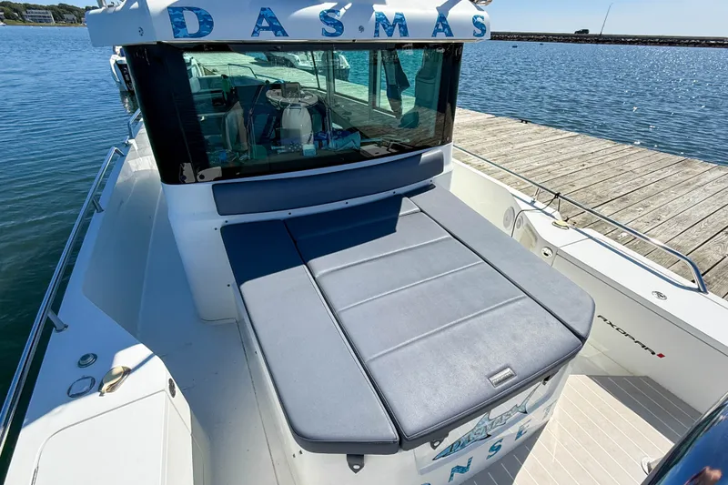 Slide: The Image of 2020 Axopar 28 Cabin boat docked by the water, featuring a cushioned deck area. - 4