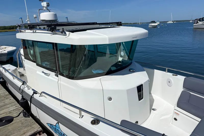 Slide: The Image of 2020 Axopar 28 Cabin boat docked on a sunny day, featuring sleek design and spacious seating. - 7