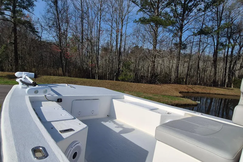 Slide: The Image of 2024 May-Craft 22 Hancock Skiff boat interior with seating, near a wooded pond. - 9
