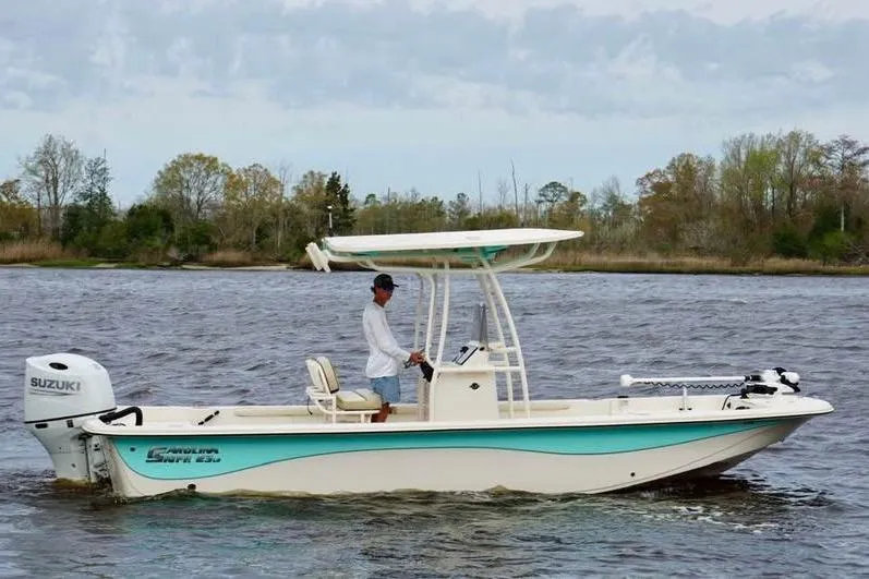 The Image of 2024 Carolina Skiff 23 LS boat cruising on a river with a person at the helm. - 0