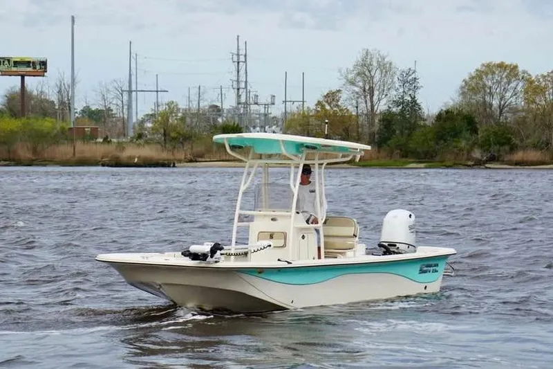 Slide: The Image of 2024 Carolina Skiff 23 LS boat cruising on a river with scenic background. - 2