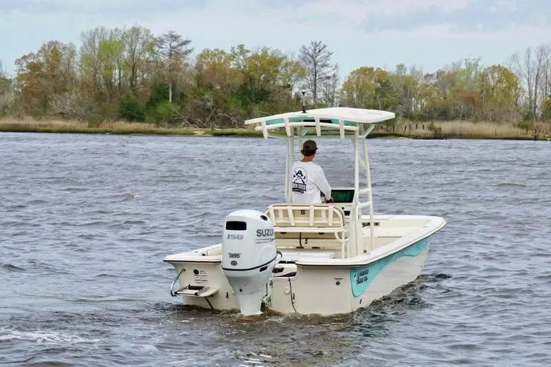 Slide: The Image of 2024 Carolina Skiff 23 LS boat cruising on a river with a Suzuki outboard motor. - 3